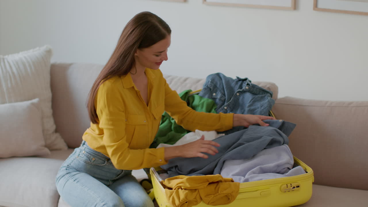 Woman Packing Clothes into a Yellow Suitcase