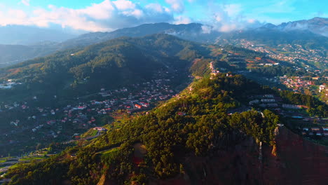 mountains with lush greenery and lots of houses. thick cloudscape floating above the rocks. panorama of the madeira islands, portugal from top.