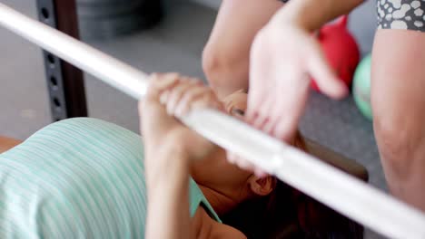 Mujer-Birracial-Determinada-E-Inalterada-Entrenando-Con-Pesas-En-El-Banco-Del-Gimnasio-Presionando-La-Barra,-En-Cámara-Lenta