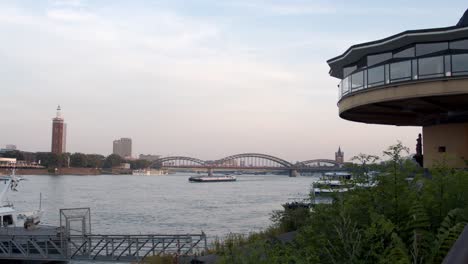 Colonia,-Alemania---Videoclip-De-4k-Del-Panorama-De-La-Puesta-De-Sol-Con-El-Puente-Hohenzollern-Y-Barcos-En-El-Río-Rin,-Alemania