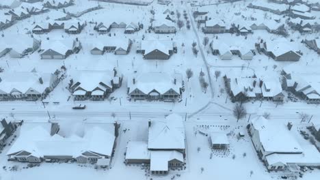 Overhead-view-of-snow-blanketed-suburban-neighborhood-with-uniform-houses