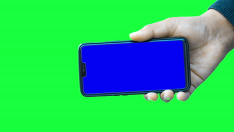 hand of a man holds a modern smartphone mockup against the green screen chroma key