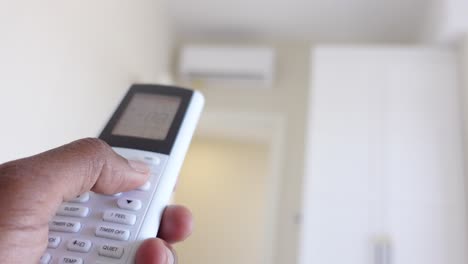 close-up of a hand using an air conditioner remote control