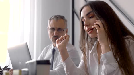 mujer joven hablando por teléfono y mirando la pantalla de su computadora portátil