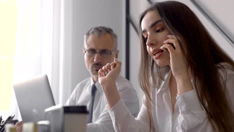 young woman talking on the phone and watching the screen of her laptop