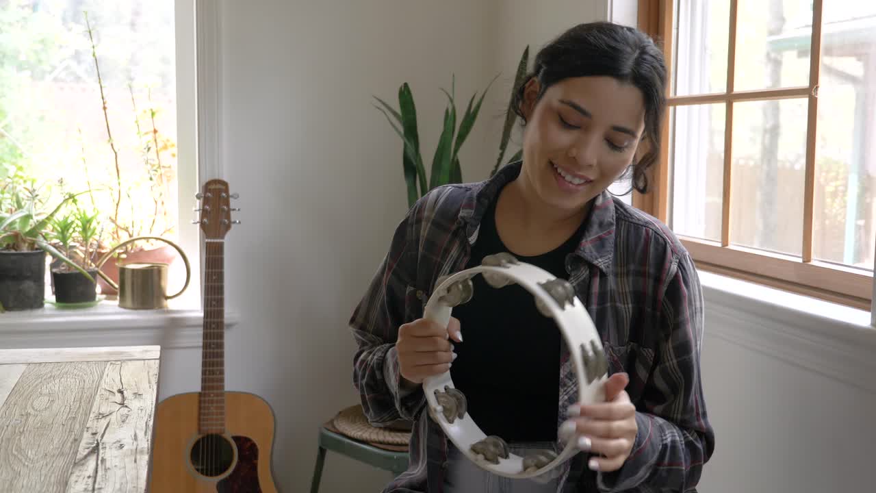 Ragazza musicista caraibica sorridente che scuote e suona il tamburello ballando a ritmo.