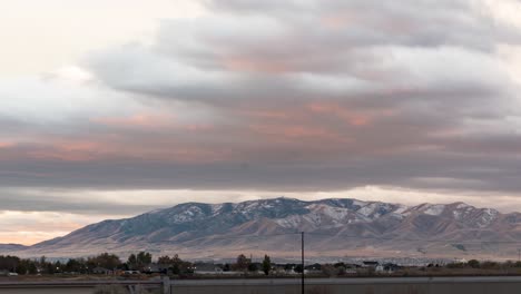 Colorido-Amanecer-Sobre-Una-Montaña-Cubierta-De-Nieve,-Luego-La-Luz-Alcanza-El-Pico-Antes-De-Que-El-Sol-Salga-Sobre-El-Paisaje-Nublado---Lapso-De-Tiempo