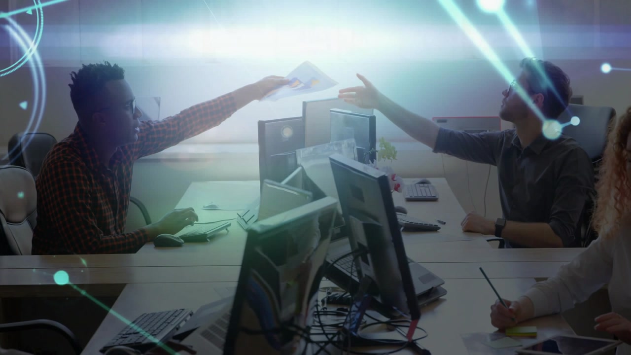Left worker picking paper extending across monitors overlay drifting right worker taking for review