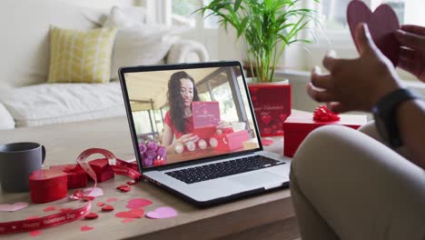 feliz mujer biracial con vitiligo leyendo tarjeta de san valentín en el día de san valentín videollamada en computadora portátil
