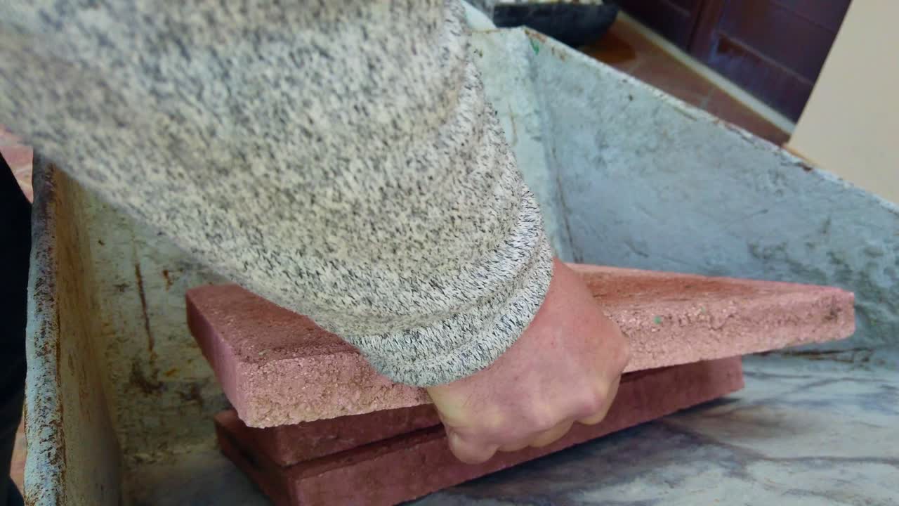 Close-up footage of three paving stones placed inside a wheelbarrow during garden landscaping work. The clip shows manual handling of materials as part of a DIY outdoor construction project