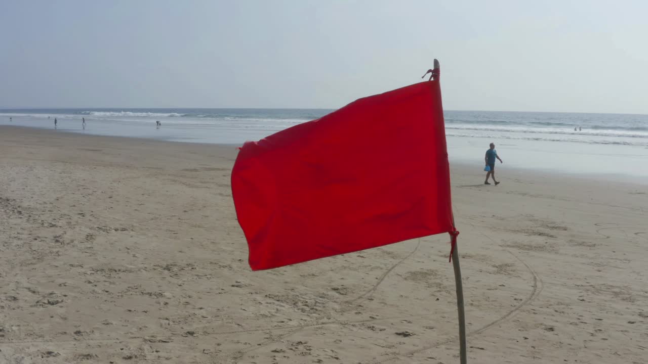 una bandera roja brillante colocada en la playa como una advertencia para las corrientes peligrosas
