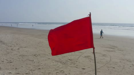 a bright red flag placed on the beach as a warning for the dangerous currents