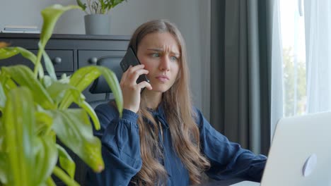 joven trabajadora en el escritorio recogiendo una llamada que muestra expresiones faciales de estrés laboral