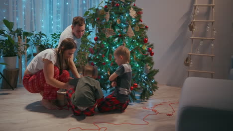 The-family-decorates-the-Christmas-tree-together.-The-father-is-a-mother-and-two-children-put-on-Christmas-trees-together.-Happy-family-on-Christmas-Eve.-High-quality-4k-footage