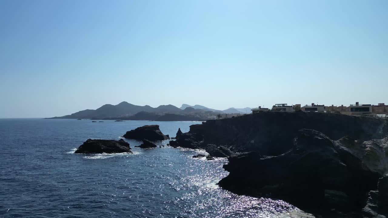 una impresionante captura de avión no tripulado de la línea de playa costera de cabo de palos durante el verano, destacando las aguas claras, y las casas hacia el final de estas tomas