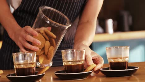 waitress placing cookies next to tea cup