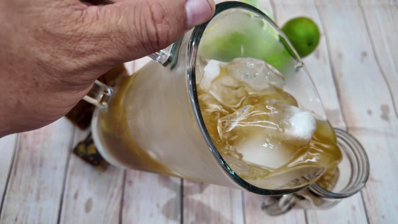 Top-down view of hand pouring traditional Venezuelan Papelón con Limón into glass