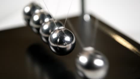 mano poniendo una simple cuna de newtons en movimiento a la luz del sol, macro, primer plano. bolas de metal balanceándose y desacelerando. moviendo algo, concepto de inercia, ciencia, divertido juguete de lección de física, tiempo real