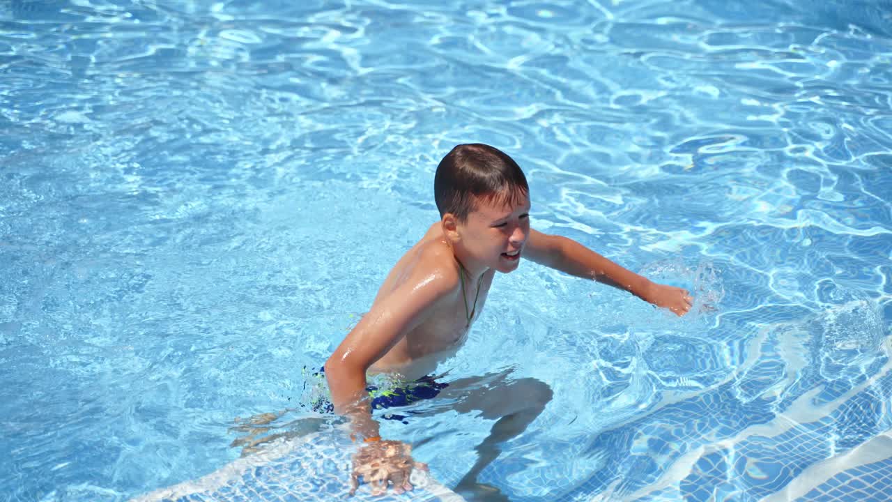 Happy child on summer vacation. Boy having fun in the swimming pool. Teenager going out of the pool.