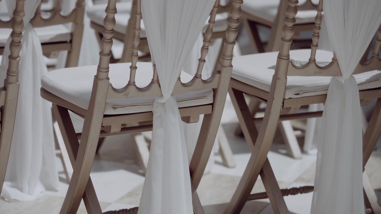 Sillas Chiavari con cojines blancos y lazos de tela en un salón de bodas