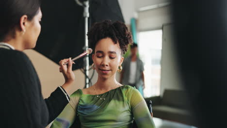 makeup artist applying makeup to model in photo studio