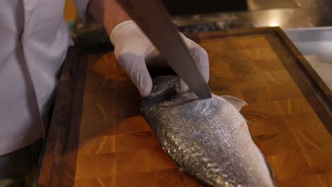 chef skilfully slicing fresh fish on cutting board