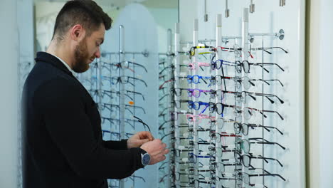 man trying new eyeglasses. young man checking new glasses at optician retail store