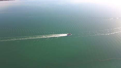 Aerial-top-view-following-Boat-cruising-on-Port-Pirie-river,-Sunlight-reflection-on-water,-Australia