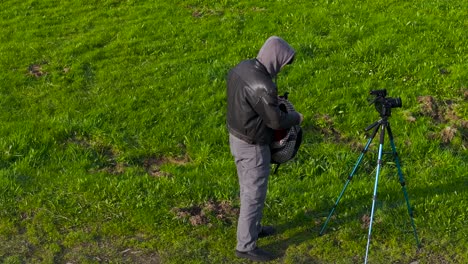 Fotograf,-Mann,-Der-Ein-Kamerastativ-Auf-Der-Wiese-Aufstellt---Weitwinkelaufnahme