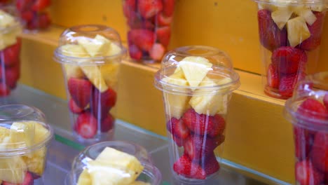 fresh strawberries and pineapple in plastic cups