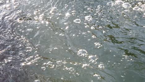 cámara lenta del agua entre rocas y hielo, formando burbujas y ondas en la superficie