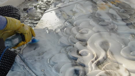 sculptor in workwear grinding white marble stone with hand machine at the working space, da nang city, vietnam