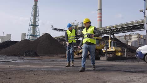 two men carrying a drone getting ready to record this industrial site