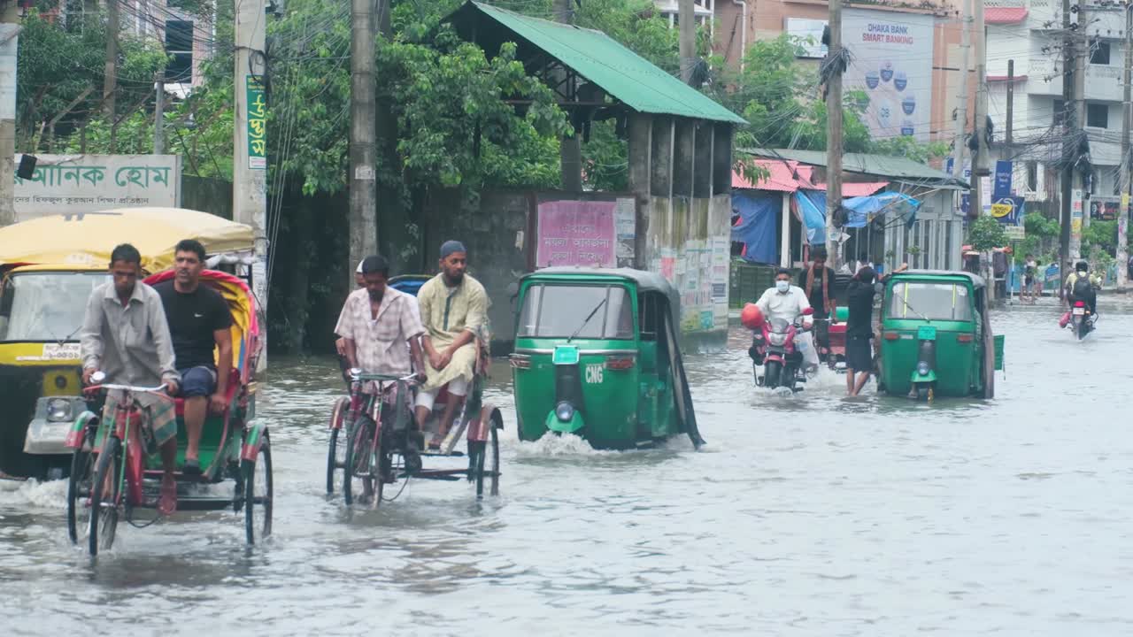 Bangladesh rickshaw bikes driving on submerged monsoon flooded roads on downtown Sylhet city street