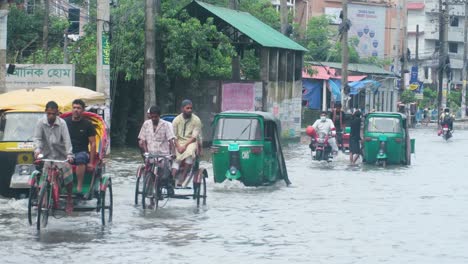 bangladesh rickshaw bikes driving on submerged monsoon flooded roads on downtown sylhet city street