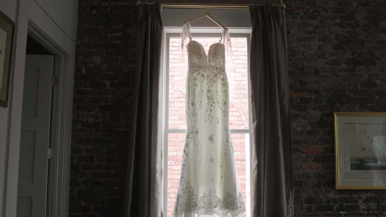 Wedding dress hung on a window in slow motion wide shot
