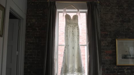 Wedding-dress-hung-on-a-window-in-slow-motion-wide-shot