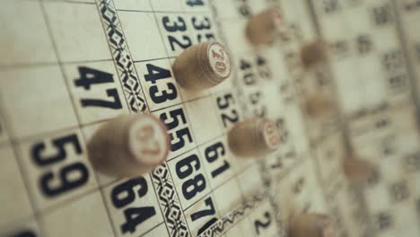 un video macro vertical de un tablero de bingo, luces de estudio, 120 fps, cámara lenta, dígitos de chips de madera, imágenes en bruto, juego de mesa de lotería vintage, números de cartas, grúa tirando hacia atrás movimiento de ensueño