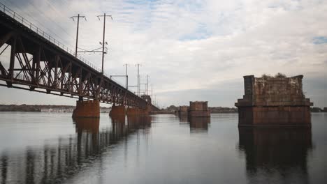 Timelapse-De-La-Bahía-De-Chesapeake-Con-Nubes-Pasando-Y-Trenes-Pasando-A-Toda-Velocidad-Con-Reflejos-En-Las-Aguas-Tranquilas.