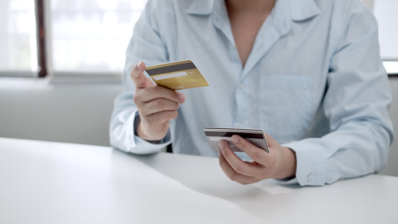 Checking his credit and debit cards, a man is looking at the details of his bankcards.