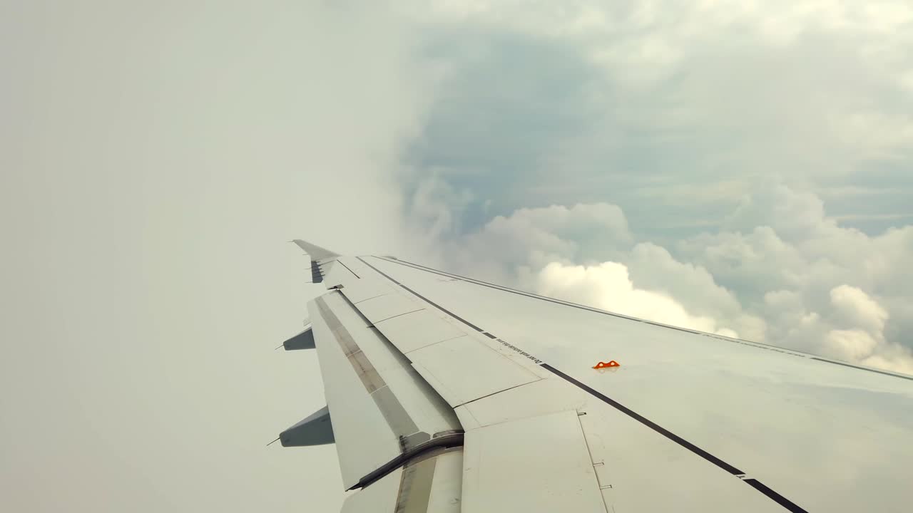 Witness a breathtaking view from an airplane wing as it soars above the clouds during sunset. The golden light reflects off the wing and creates a serene atmosphere