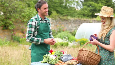Pretty blonde buying peppers from smiling gardener