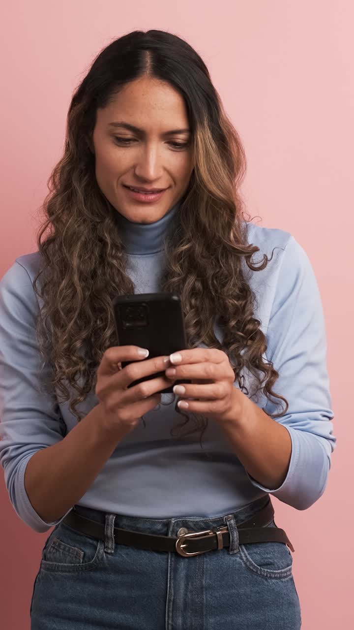 Smiling adult hispanic woman using mobile phone. Vertical footage