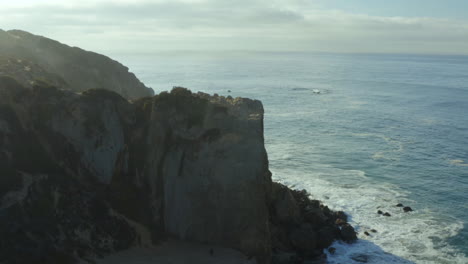 Toma-Aérea-De-Establecimiento-De-Las-Olas-Rompiendo-Contra-Las-Rocas-En-La-Playa