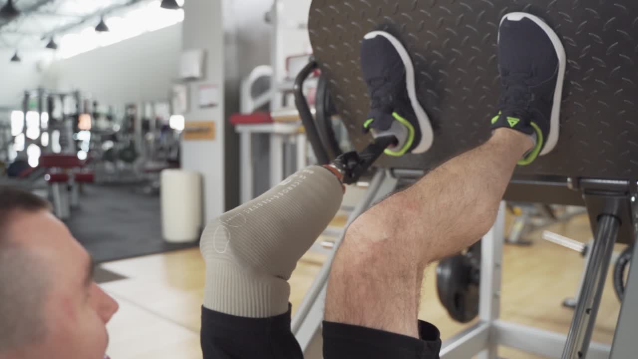 Disabled athletic with prosthetic leg do heavy exercises for legs at the gym in slow motion