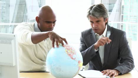 dos ambiciosos hombres de negocios mirando un globo terrestre