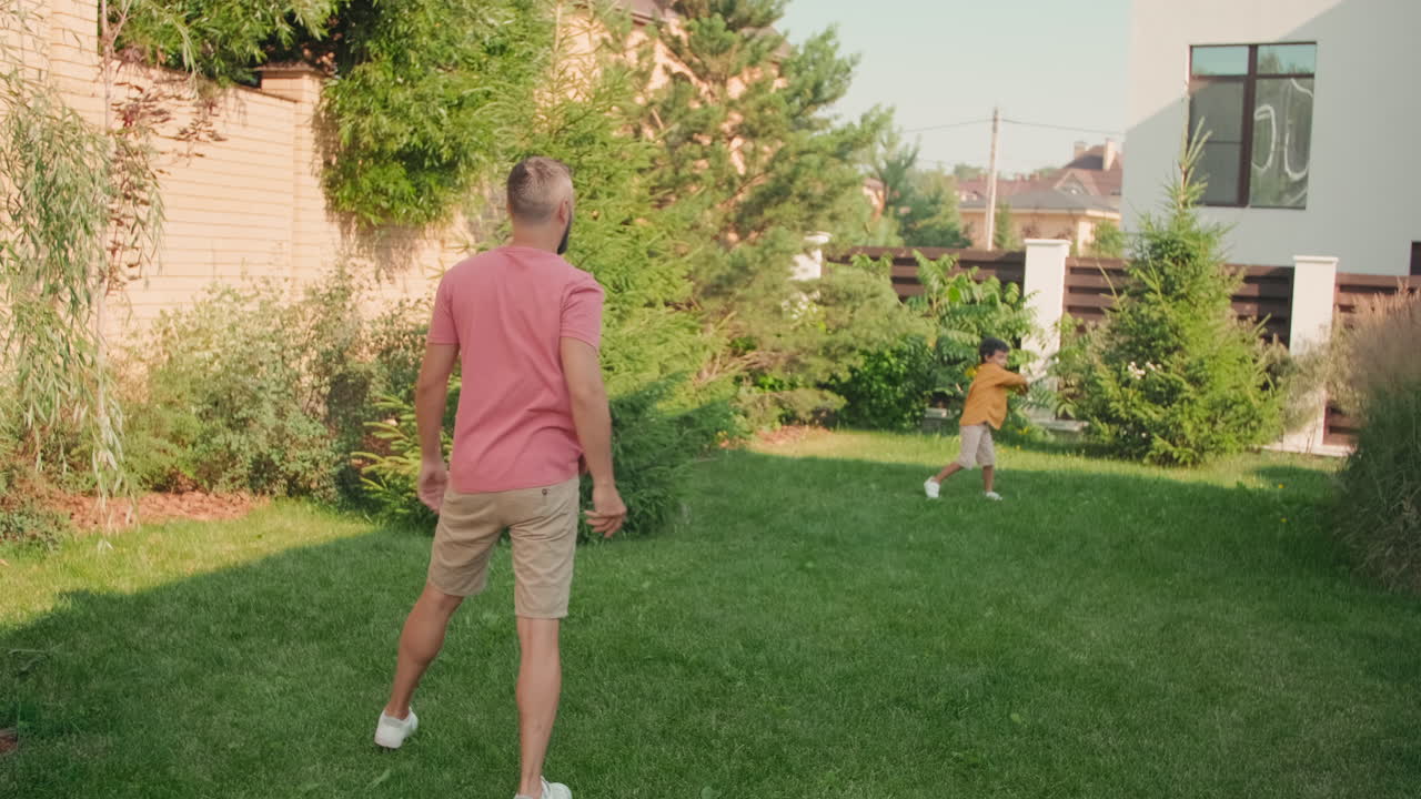 Father And Son Playing Frisbee In Backyard