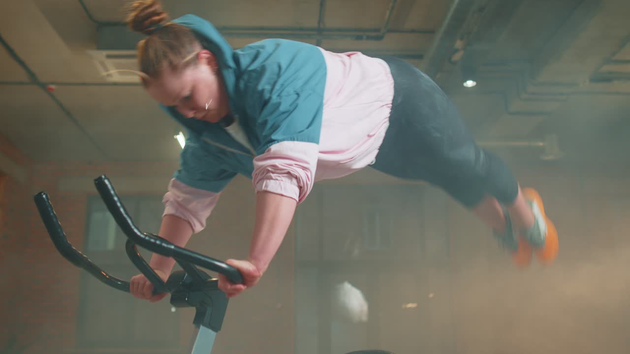 Athletic woman riding on spinning stationary bike training routine in haze gym weight loss indoors