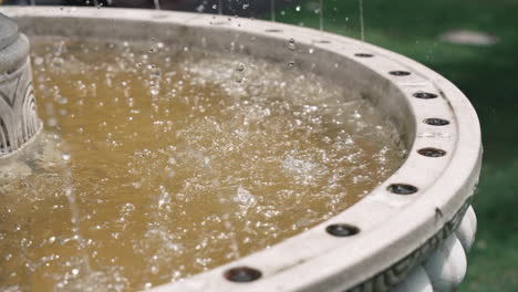 Salpicando-Agua-En-Una-Fuente-De-Mármol,-De-Cerca.-Jardín