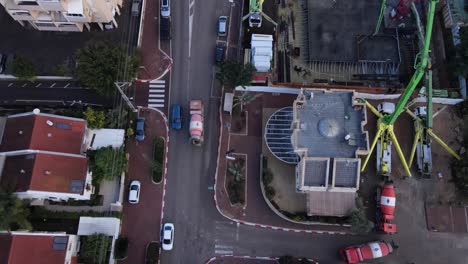 Top-down-aerial-view-of-concrete-mixer-passing-through-city-road-construction-site,-Tel-Aviv,-Israel